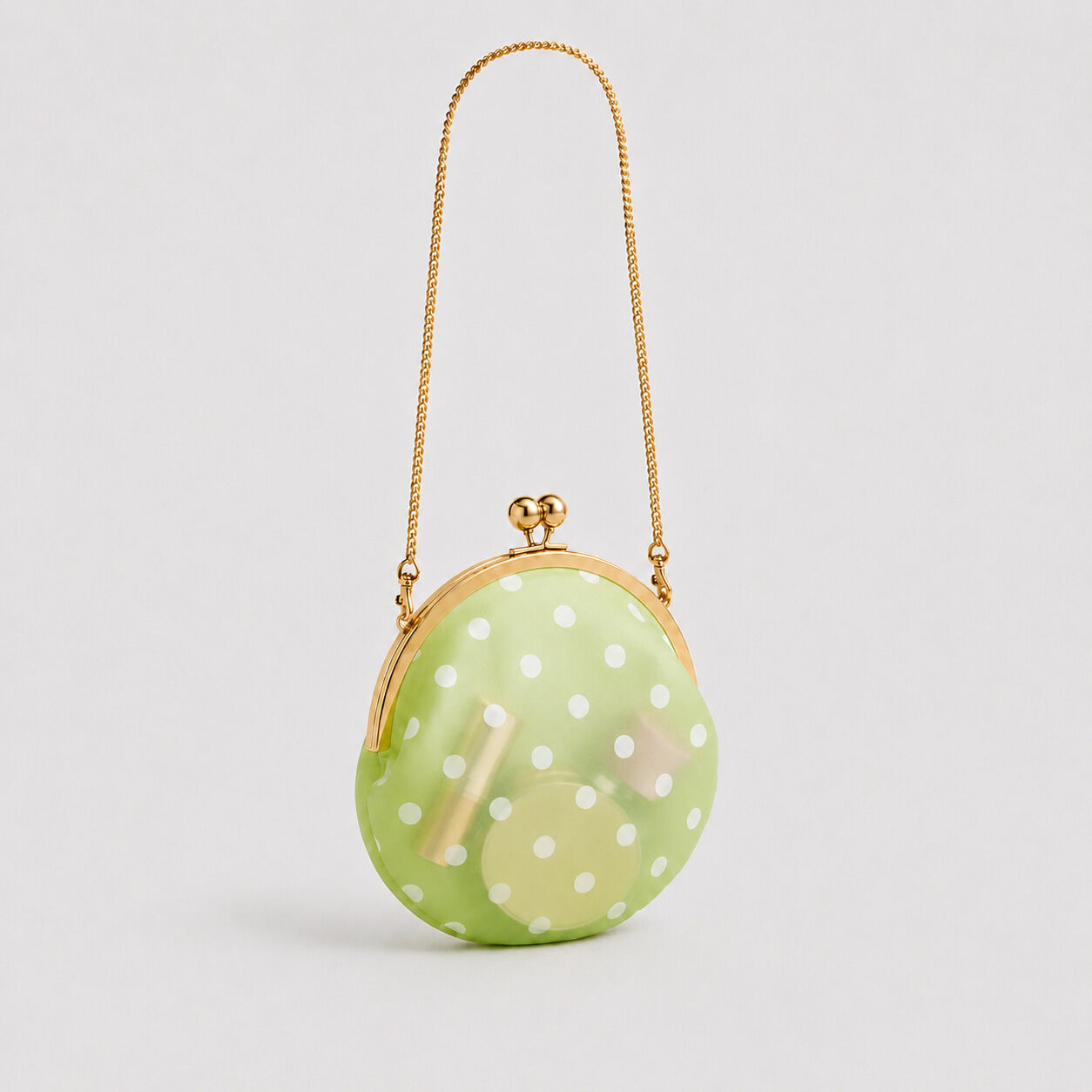 Bolso redondo de mujer de PVC transparente con estampado de lunares y herrajes metálicos, estilo parisino chic.